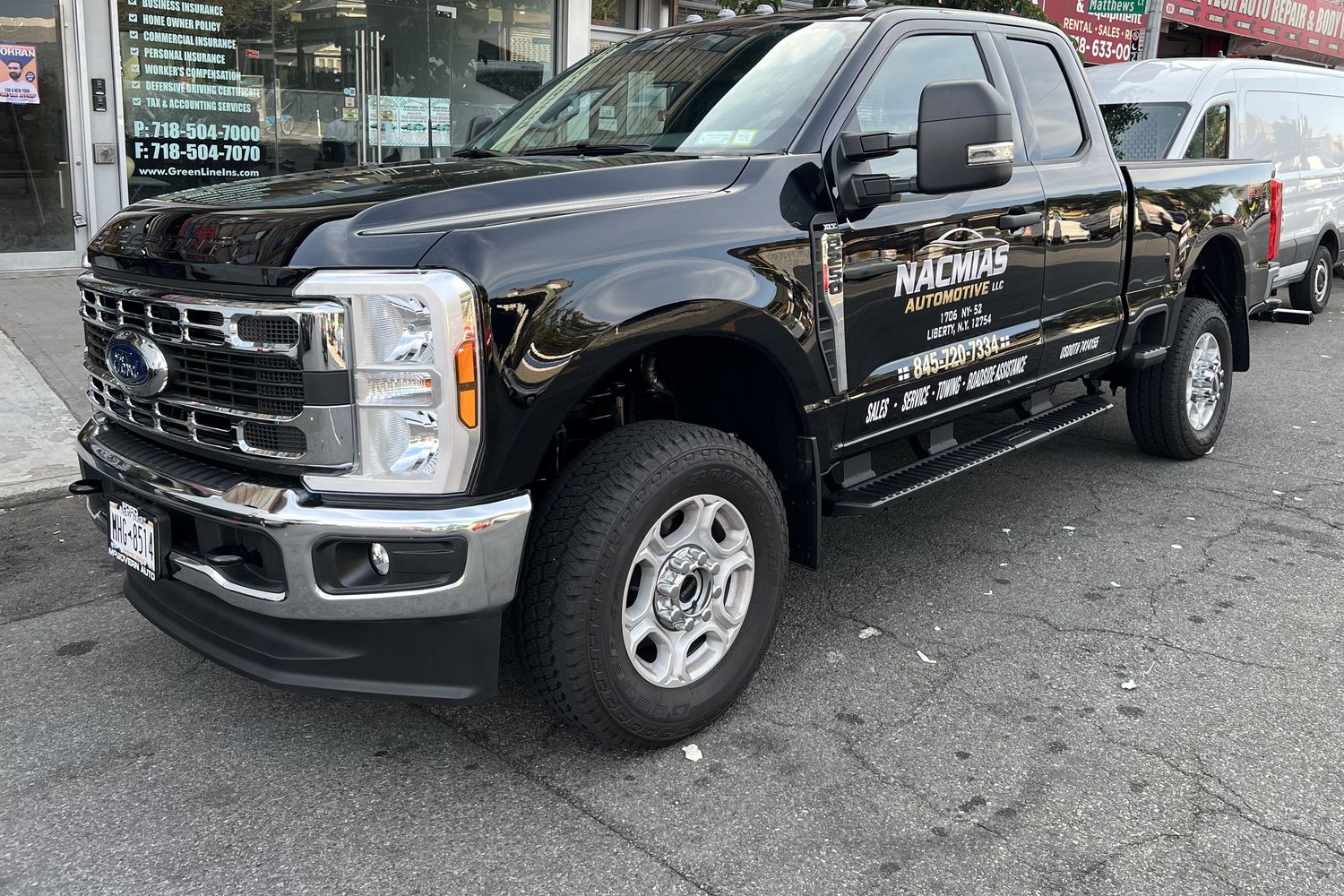 A Nacmias Automotive truck with company lettering on the door, parked on Coney Island Avenue in Brooklyn